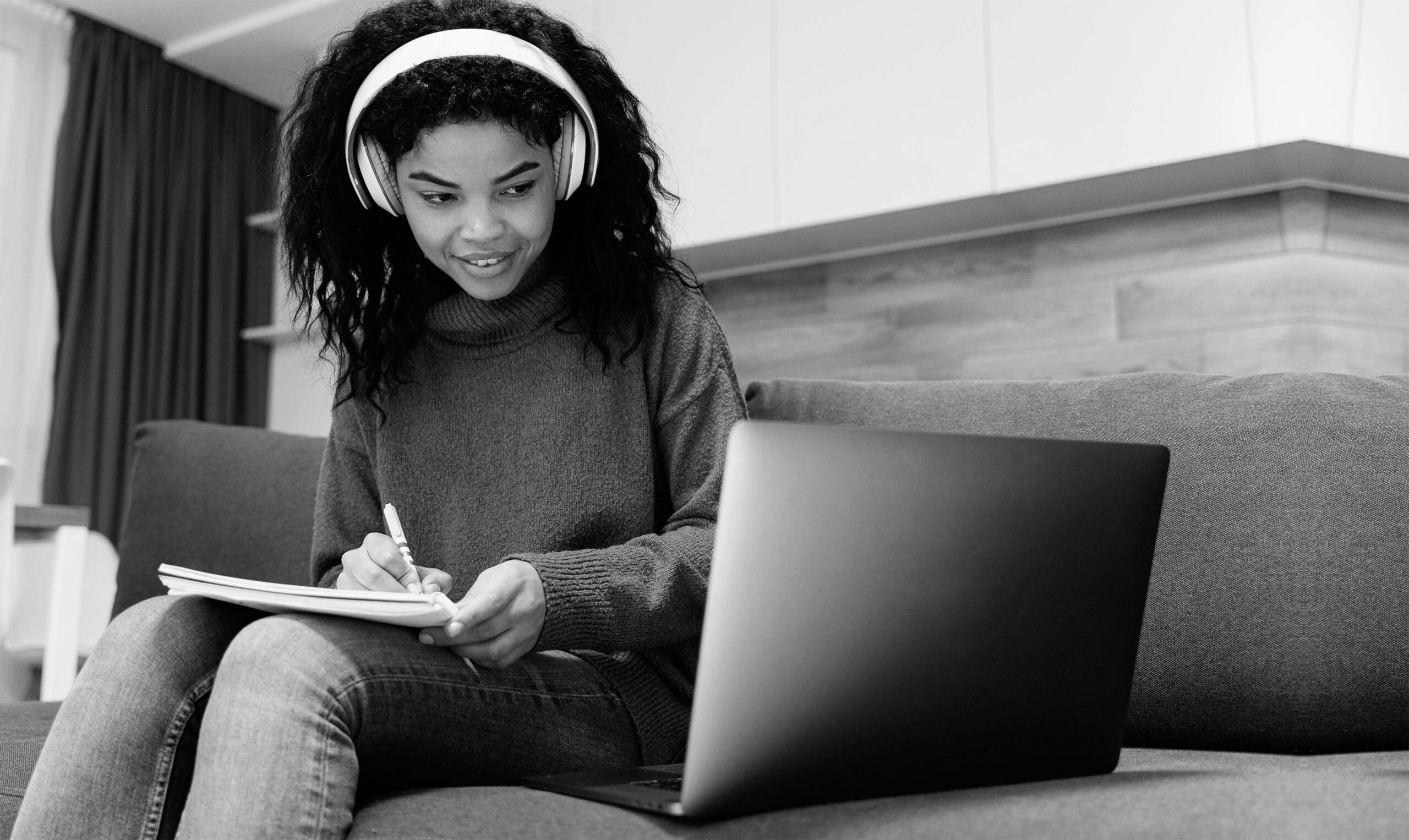 A young person studying with headphones and a laptop